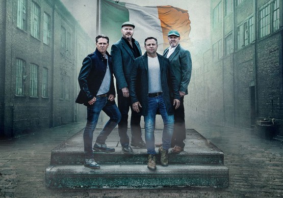 Members of the High KIngs standing in front of the flag of Ireland