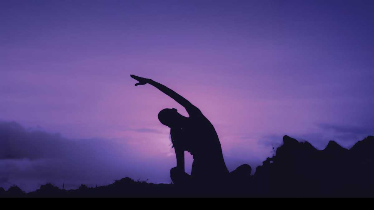 Woman doing yoga outdoors at sunrise