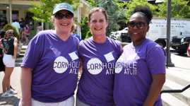 Three ladies wearing Cornhole ATL t-shirts and smiling
